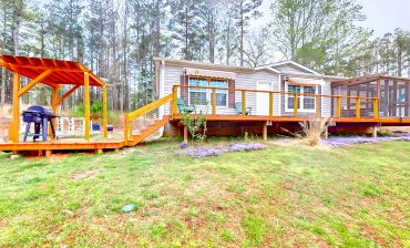 Mobile Home Exterior with A Screened-In Porch, A Deck, and A Pergola